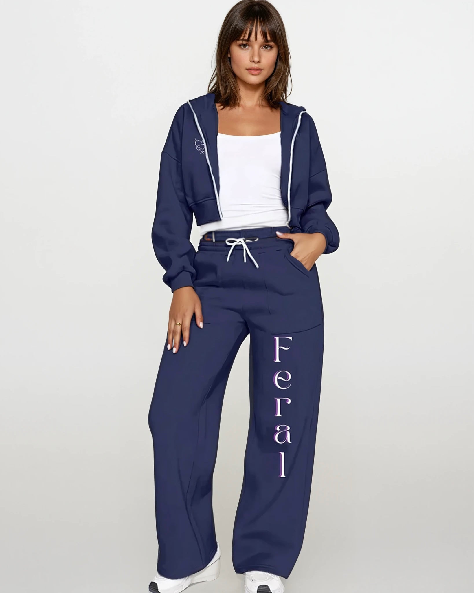 Woman wearing a navy blue tracksuit with 'Feral' text on pants against a white background