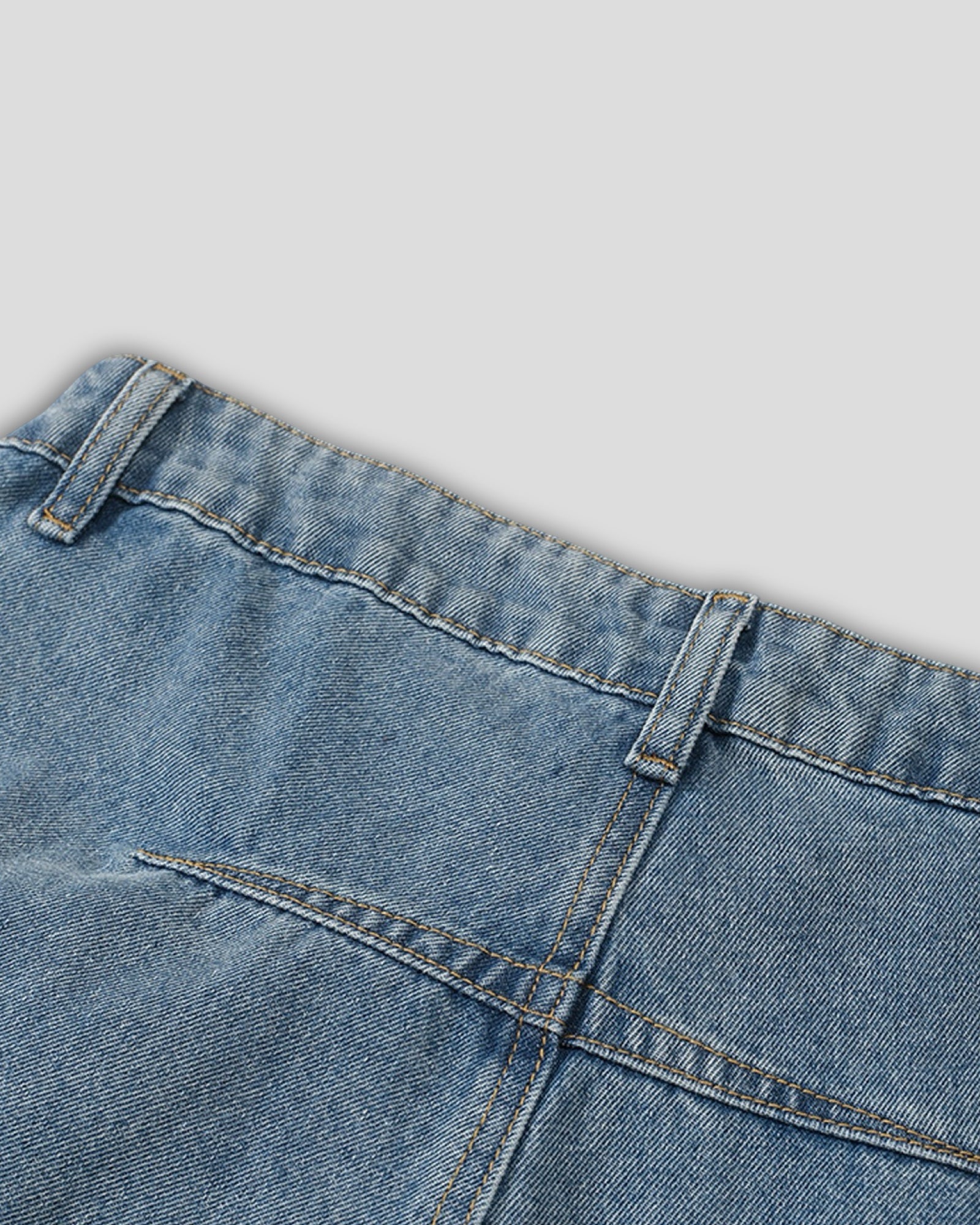 Close-up of blue denim fabric with stitching details on a light gray background