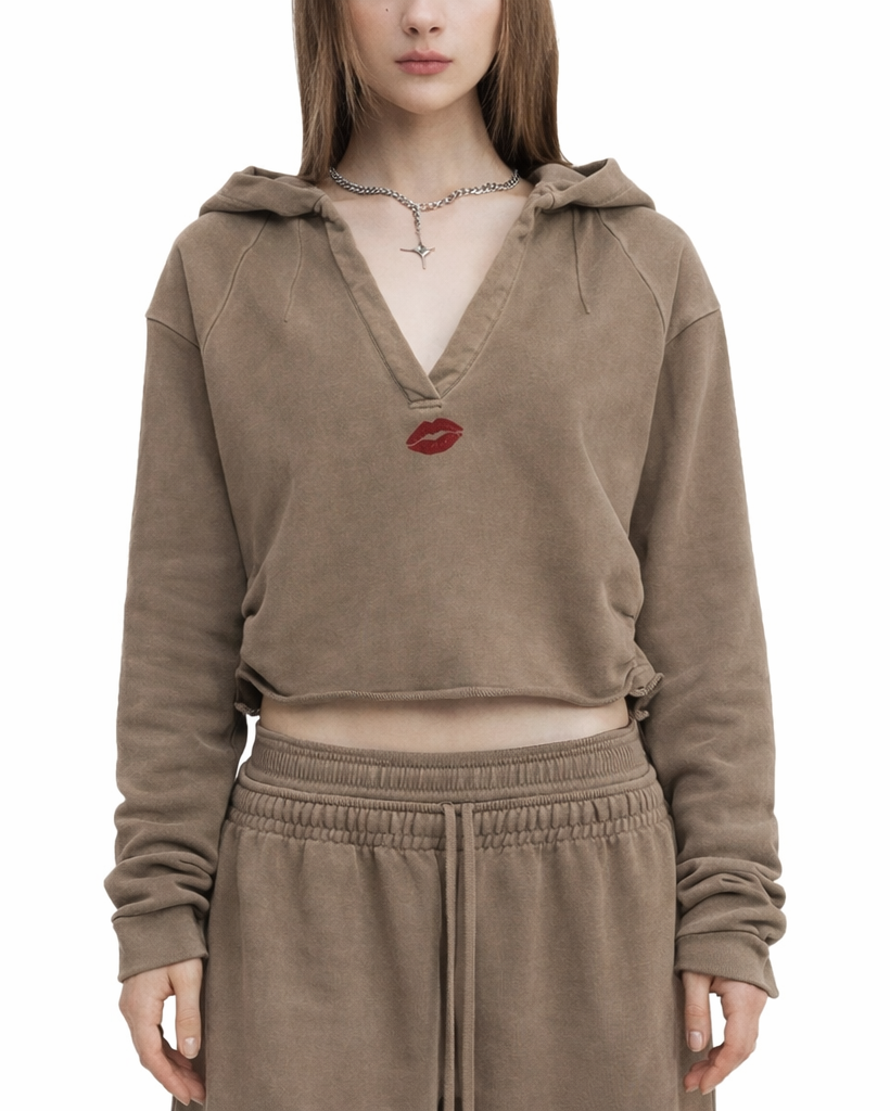 Person wearing a brown hoodie with a red lip print on a white background