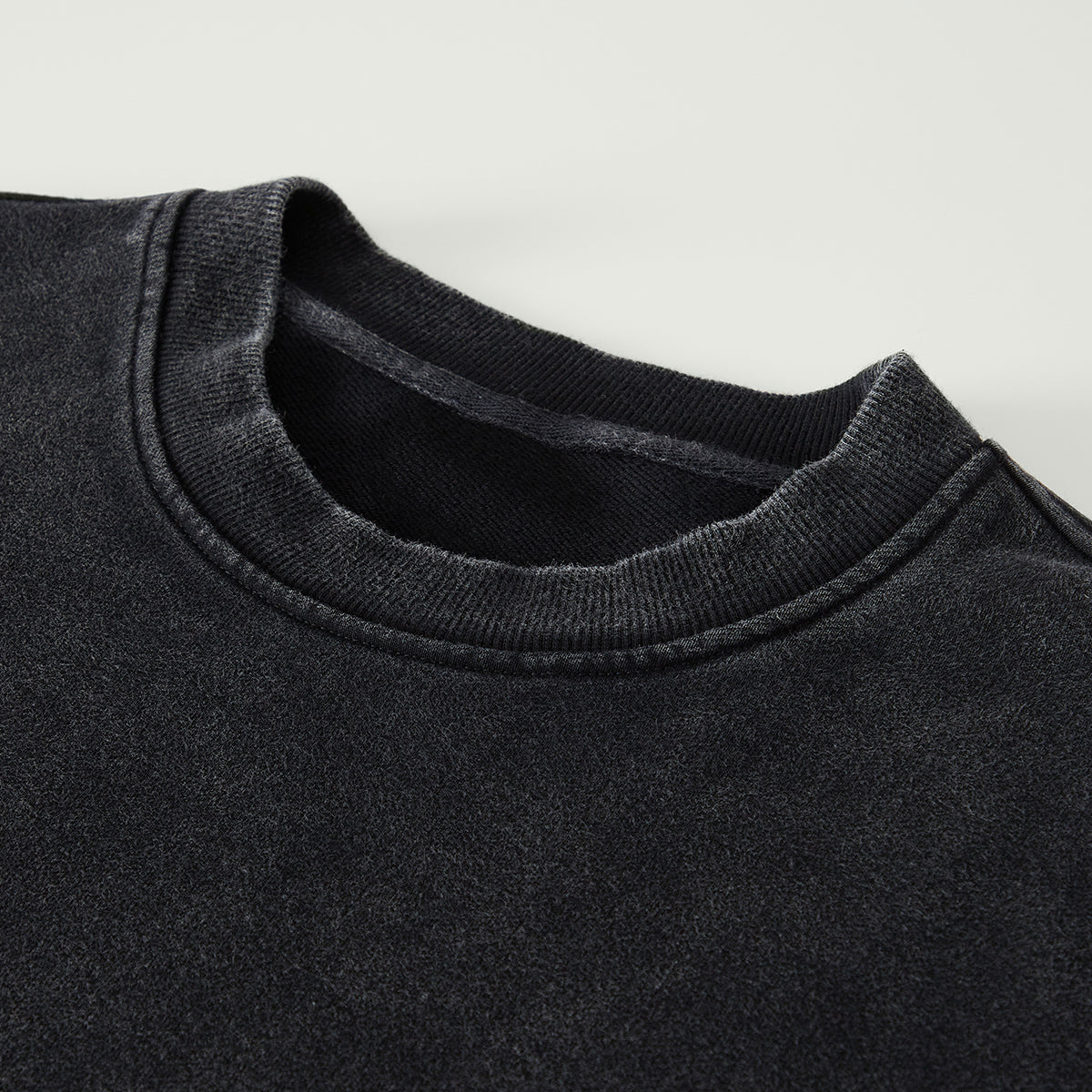 Close-up of a black sweater collar on a light gray background