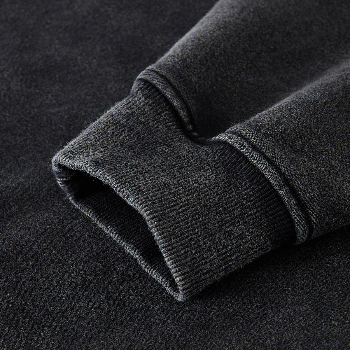 Close-up of a dark gray fleece fabric with a textured surface on a black background