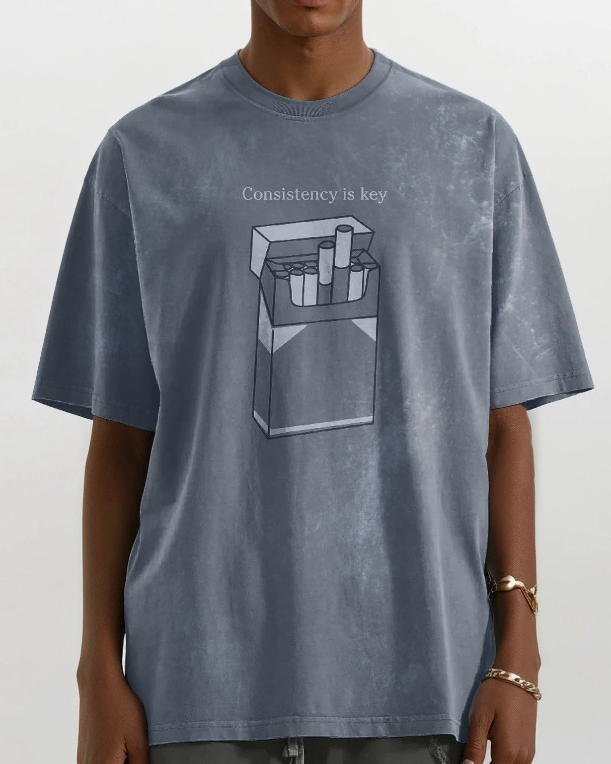 close up of a man wearing an oversized vintage wash gray heavyweight cotton t-shirt with an embroidered graphic design that reads 