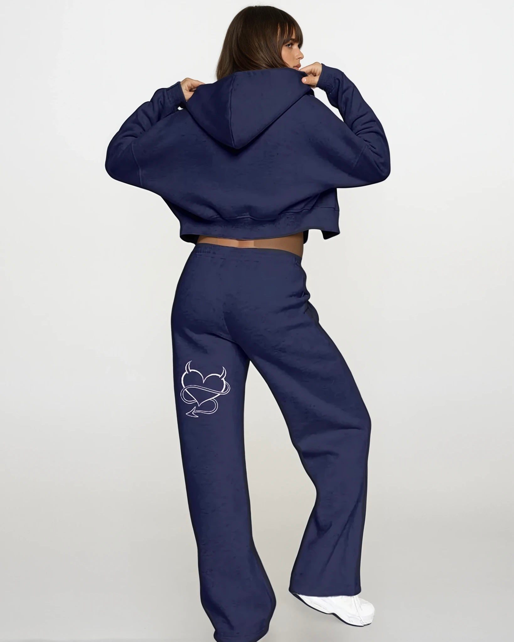 Person wearing a navy blue tracksuit with a heart design on a white background