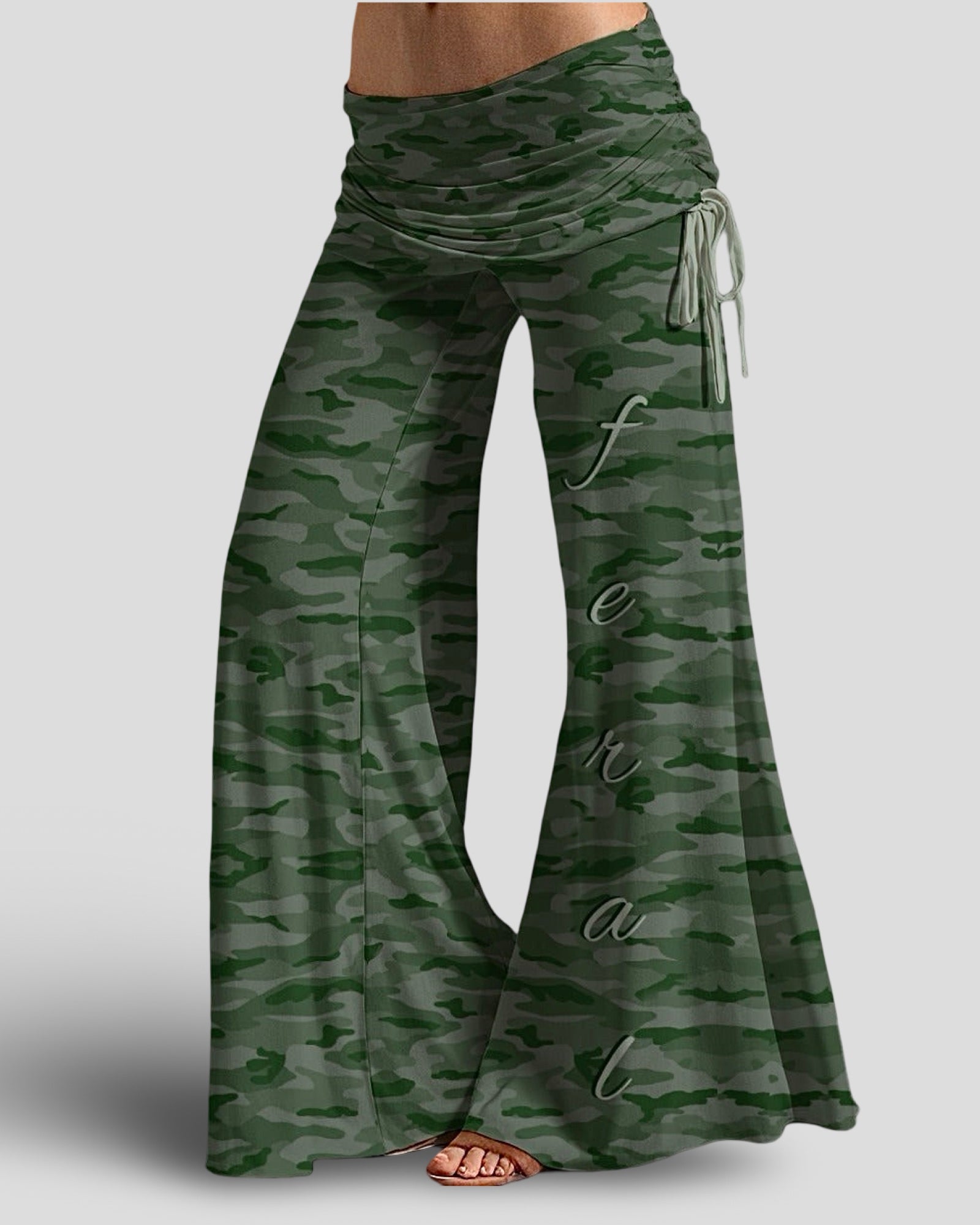 Green camouflage lounge pants with 'feral' text on a gray background