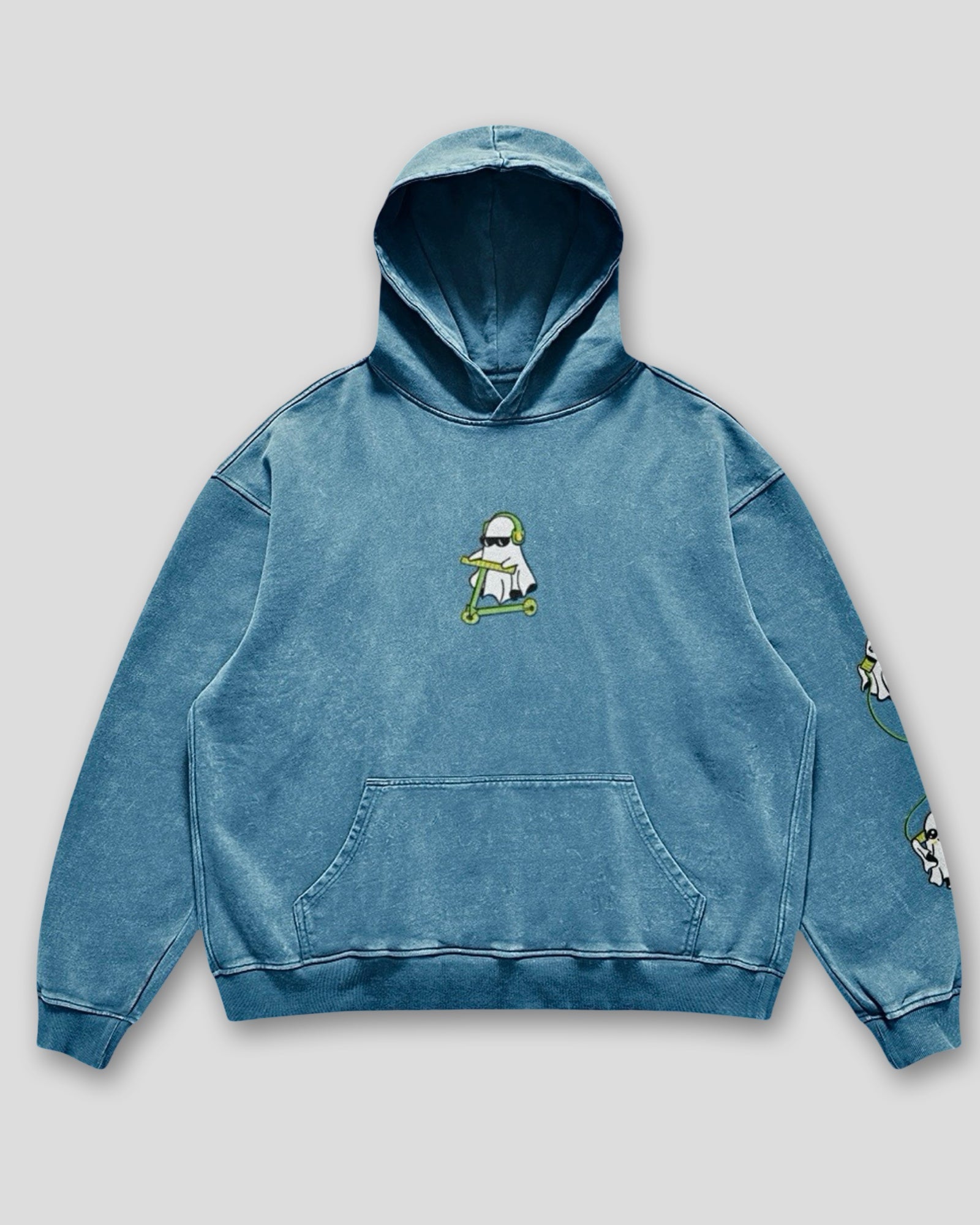 flat lay image of a denim blue vintage washed heavyweight cotton oversized hoodie with a kangaroo pocked and embroidered original ghost graphics on the front and left arm against a white background