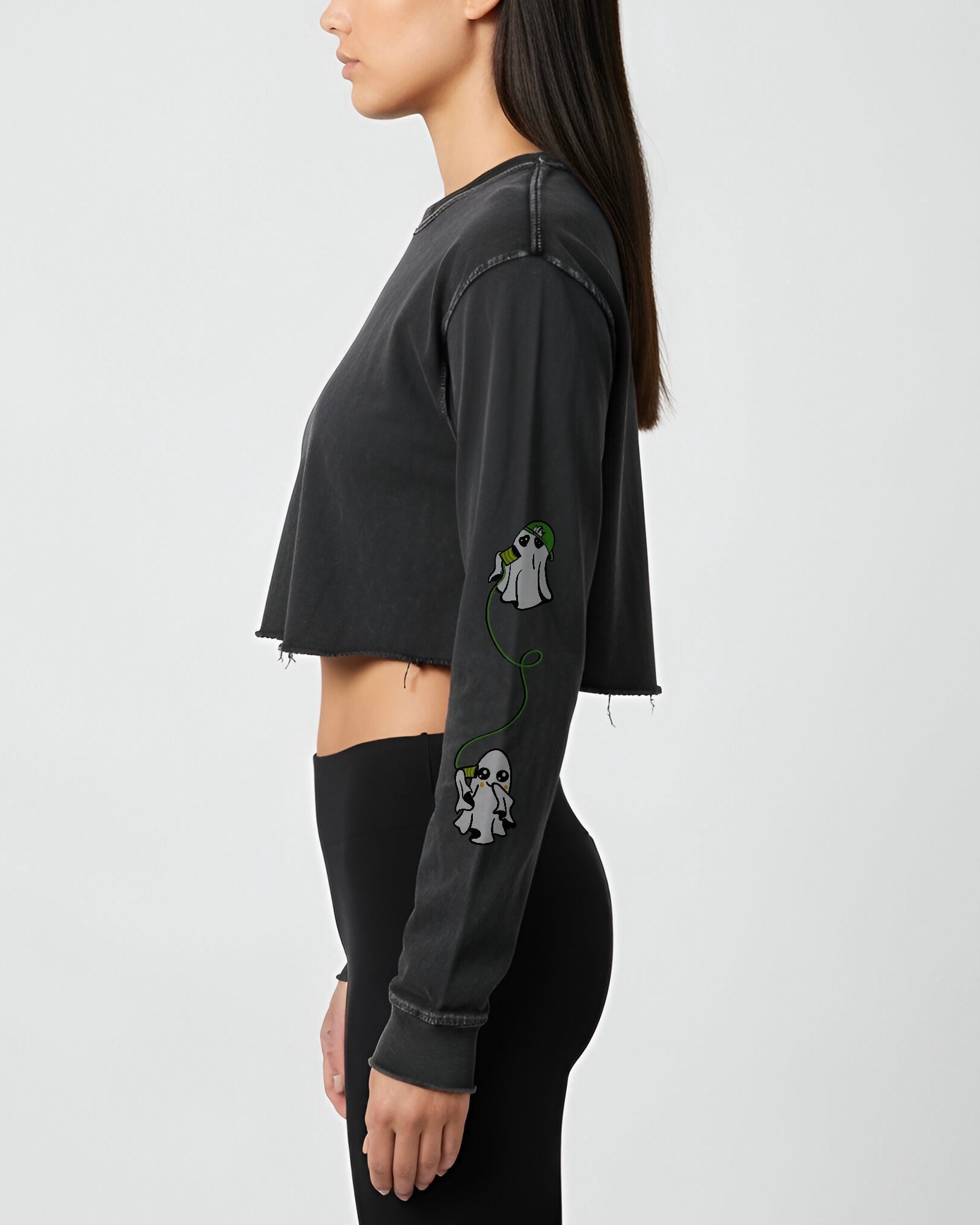 woman wearing a black long-sleeve crop top with ghost graphic designs on a white background