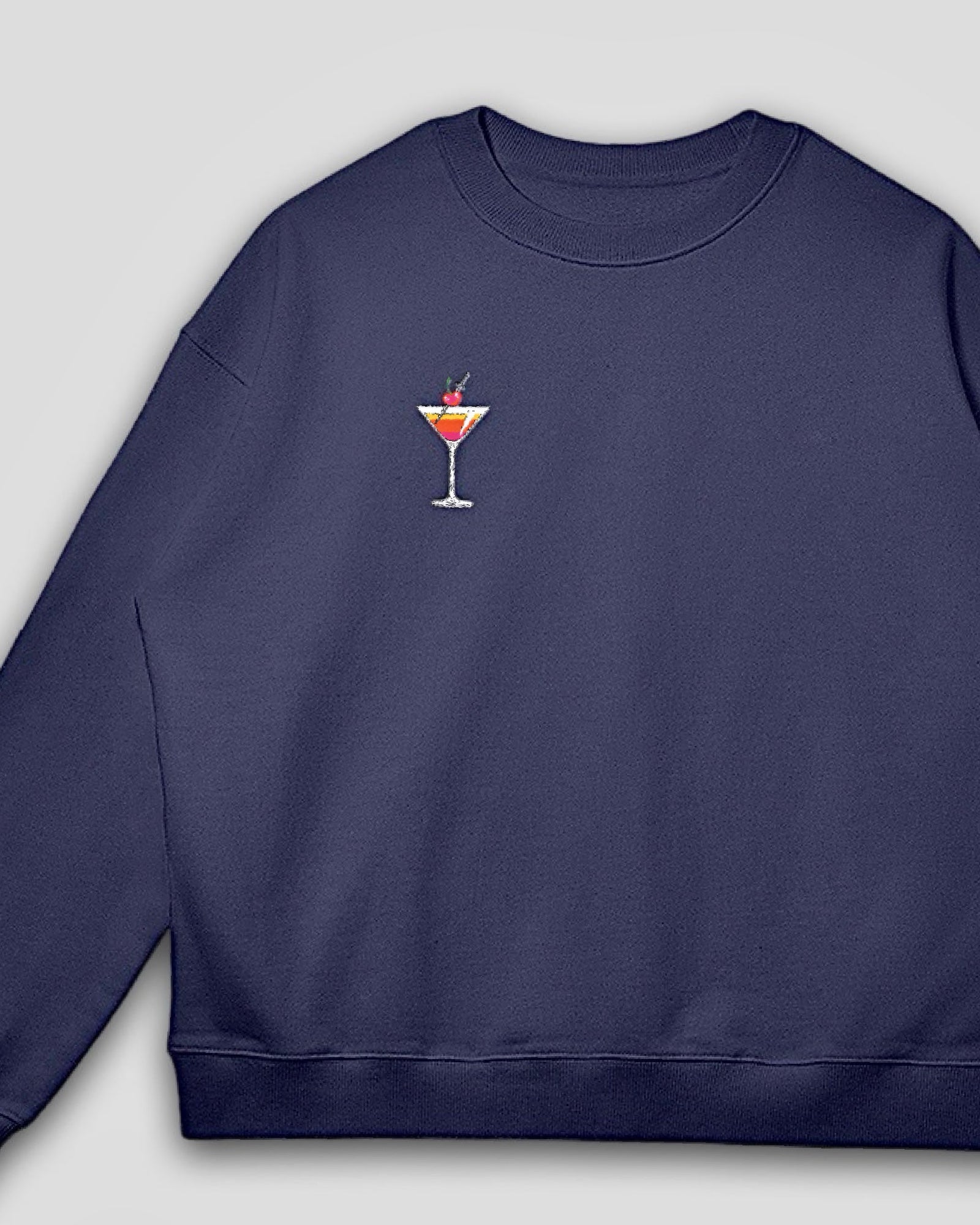flat lay image of a navy blue oversized heavyweight cotton drop shoulder embroidered premium pullover sweatshirt with embroidered martini design against a white background