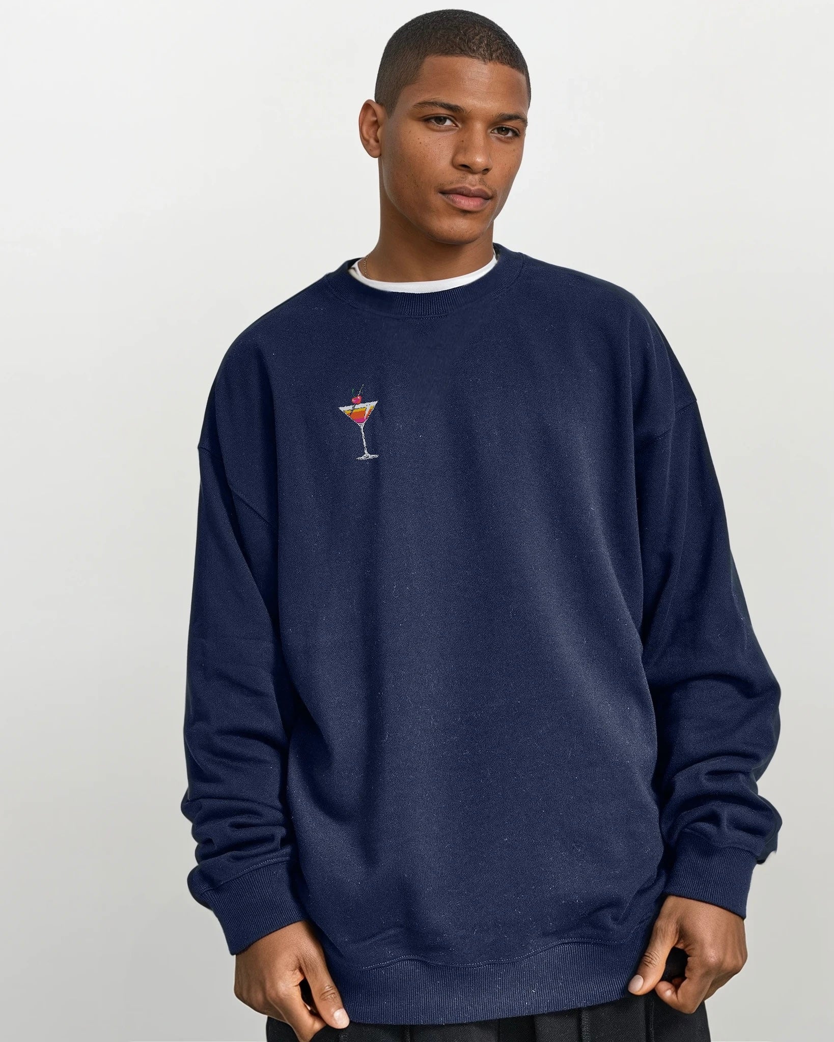 man wearing a navy blue oversized heavyweight cotton drop shoulder embroidered premium pullover sweatshirt with embroidered martini design against a white background