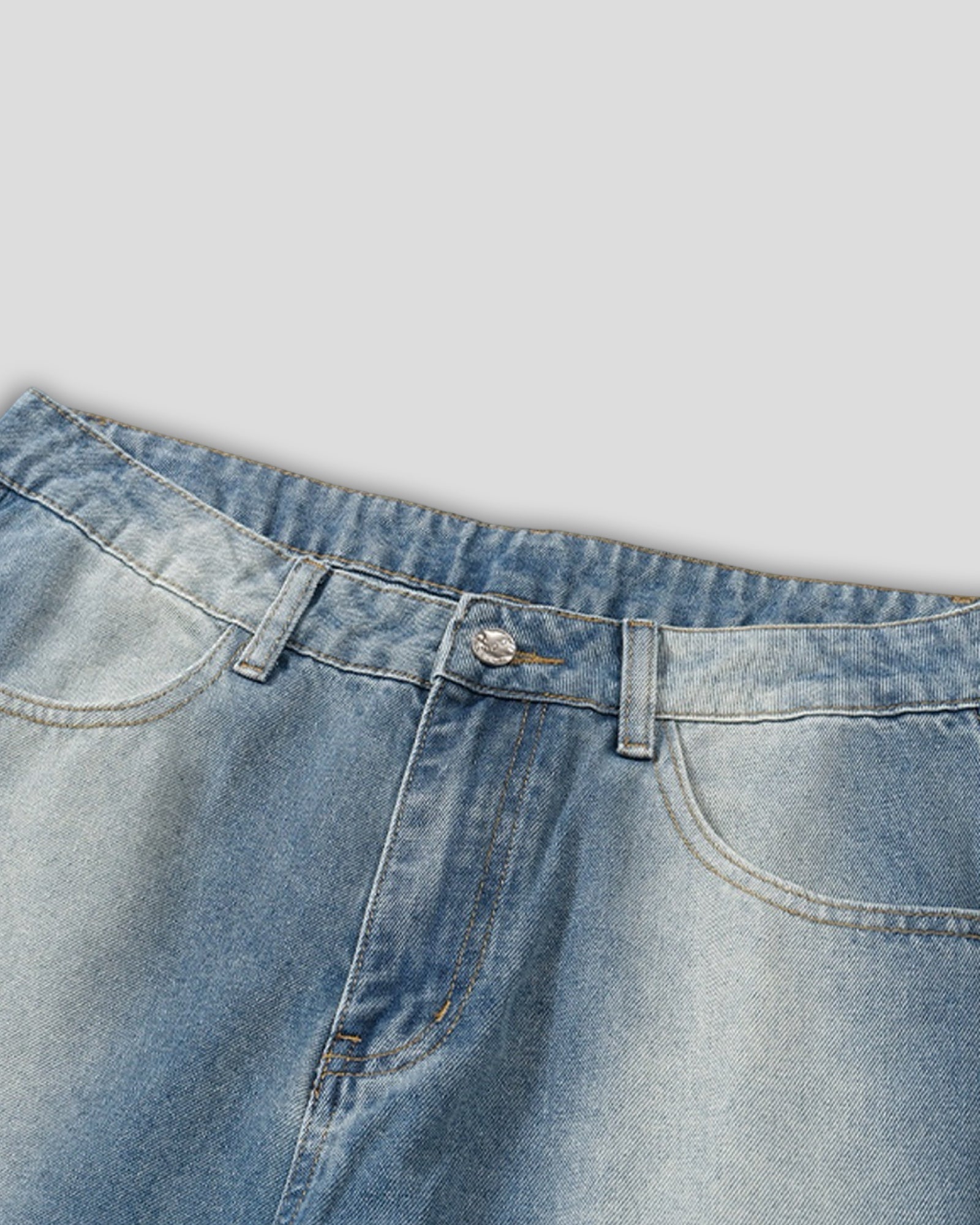 Close-up of a blue denim jeans waistband on a light gray background