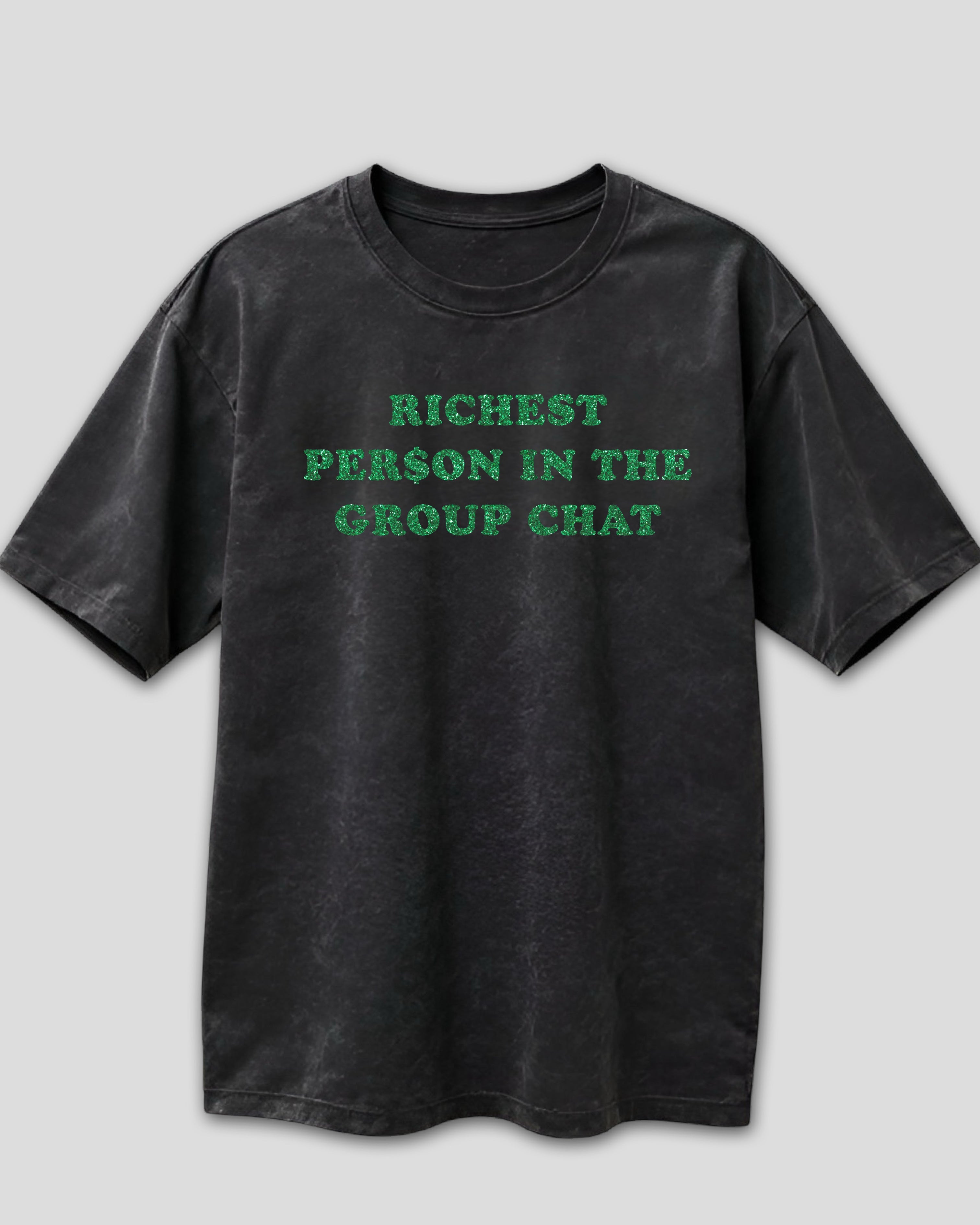Black heavyweight cotton t-shirt with green text 'RICHEST PERSON IN THE GROUP CHAT' on a light gray background