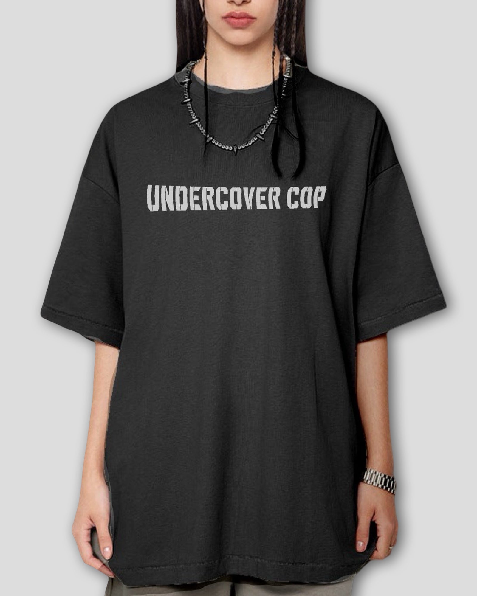 Person wearing a black heavyweight cotton oversized t-shirt with 'UNDERCOVER COP' text on a plain background