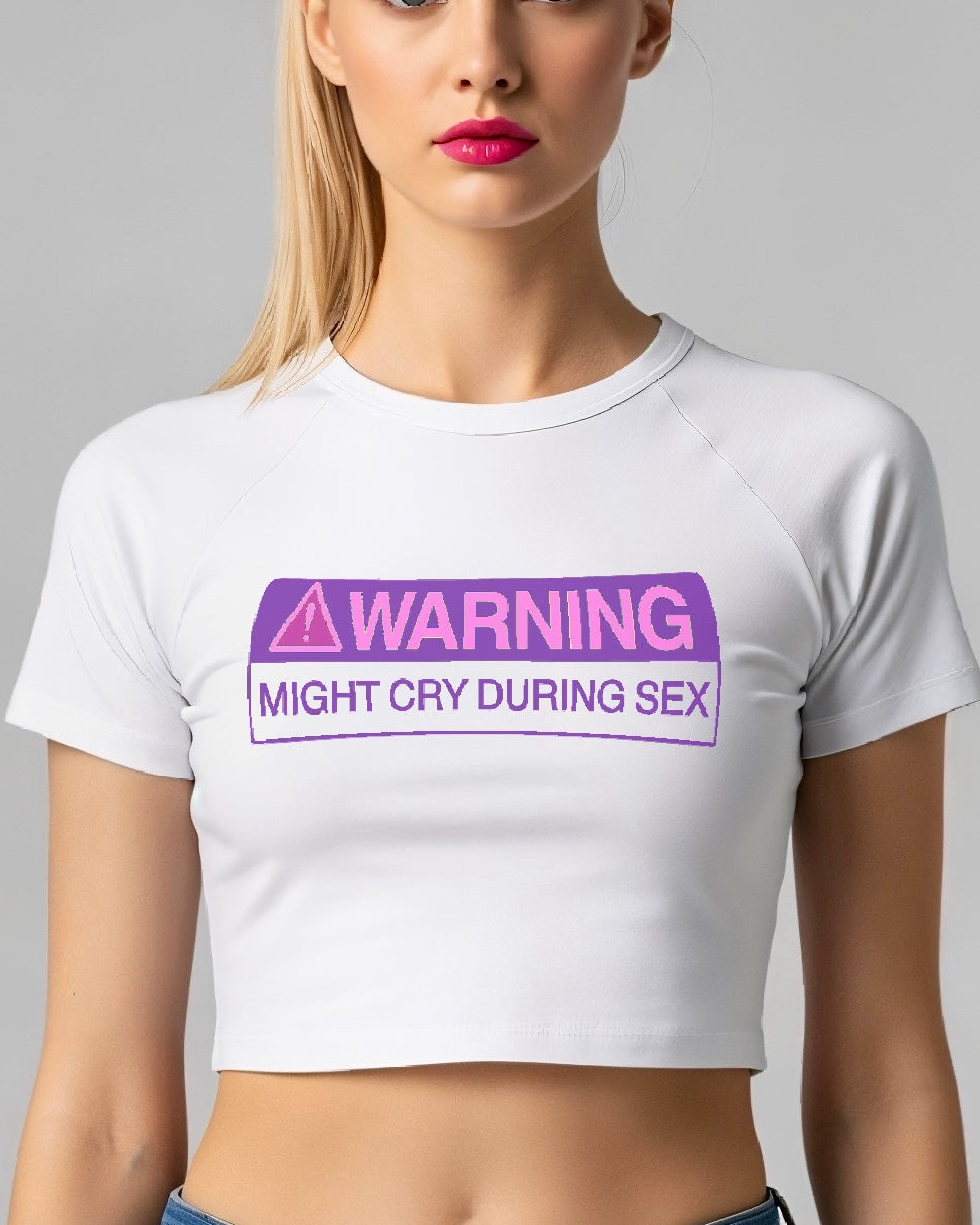 Person wearing a white baby tee with a purple warning label text.